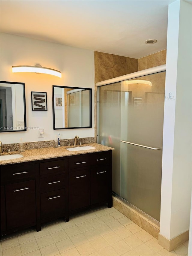 bathroom with a stall shower, double vanity, and a sink