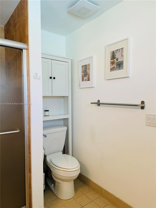 bathroom featuring toilet, tile patterned flooring, a stall shower, and baseboards