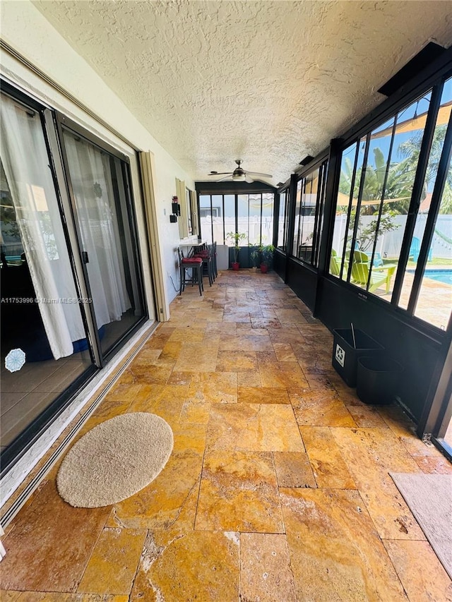 unfurnished sunroom featuring a ceiling fan
