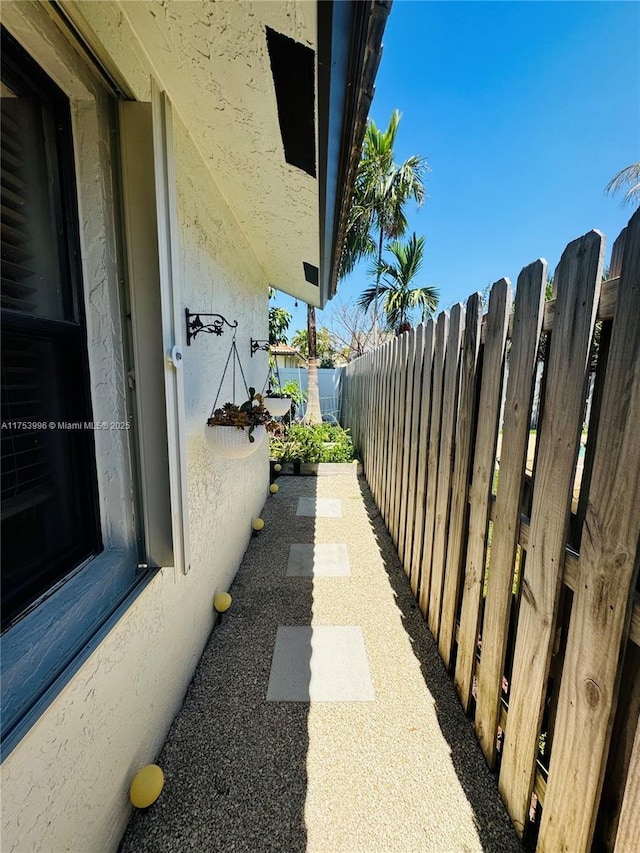 view of side of home with fence and stucco siding