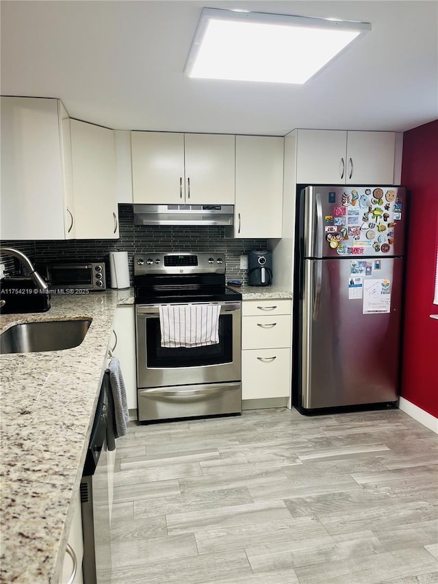 kitchen featuring appliances with stainless steel finishes, white cabinetry, a sink, and under cabinet range hood