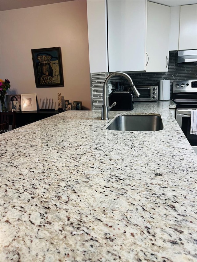 kitchen with decorative backsplash, light stone counters, extractor fan, stainless steel range with electric cooktop, and a sink