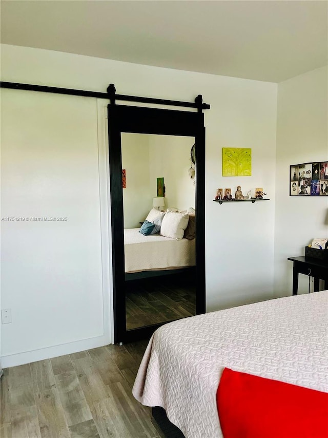 bedroom with a barn door and wood finished floors