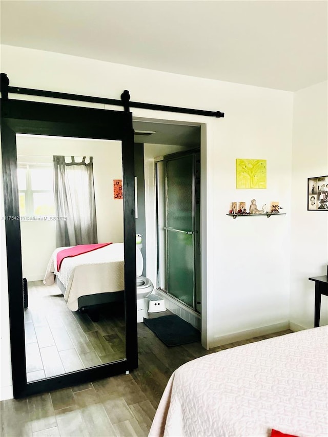 bedroom with a barn door and wood finished floors