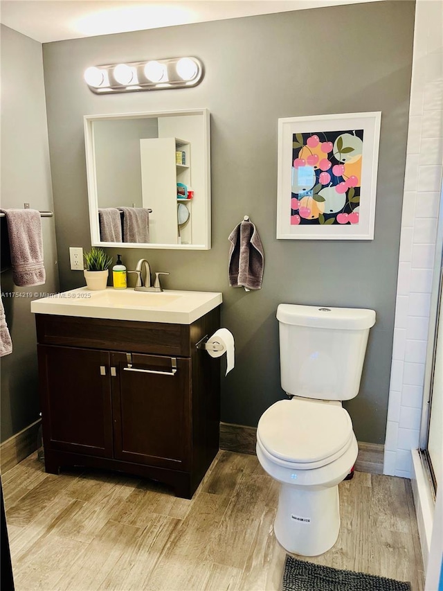 full bathroom with baseboards, a shower, toilet, wood finished floors, and vanity