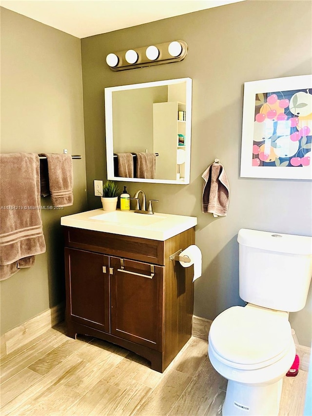 bathroom featuring toilet, wood finished floors, vanity, and baseboards