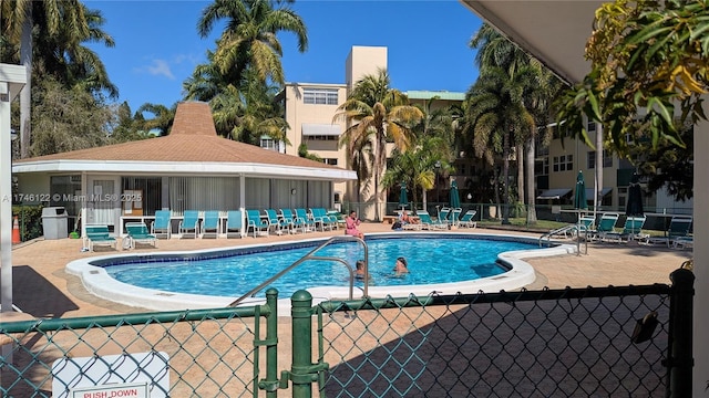 community pool with a patio and fence