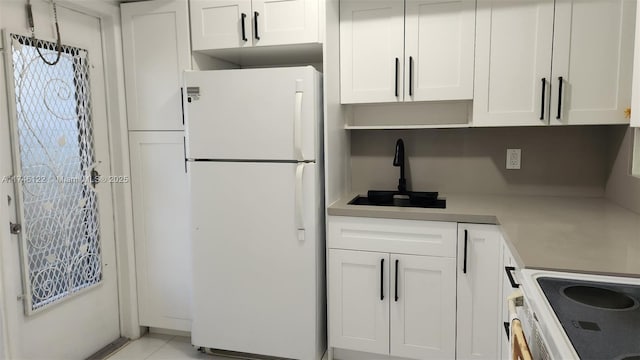 kitchen with light tile patterned floors, white cabinetry, light countertops, freestanding refrigerator, and electric range oven