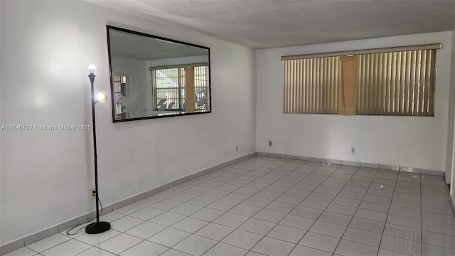 unfurnished room with light tile patterned floors and baseboards