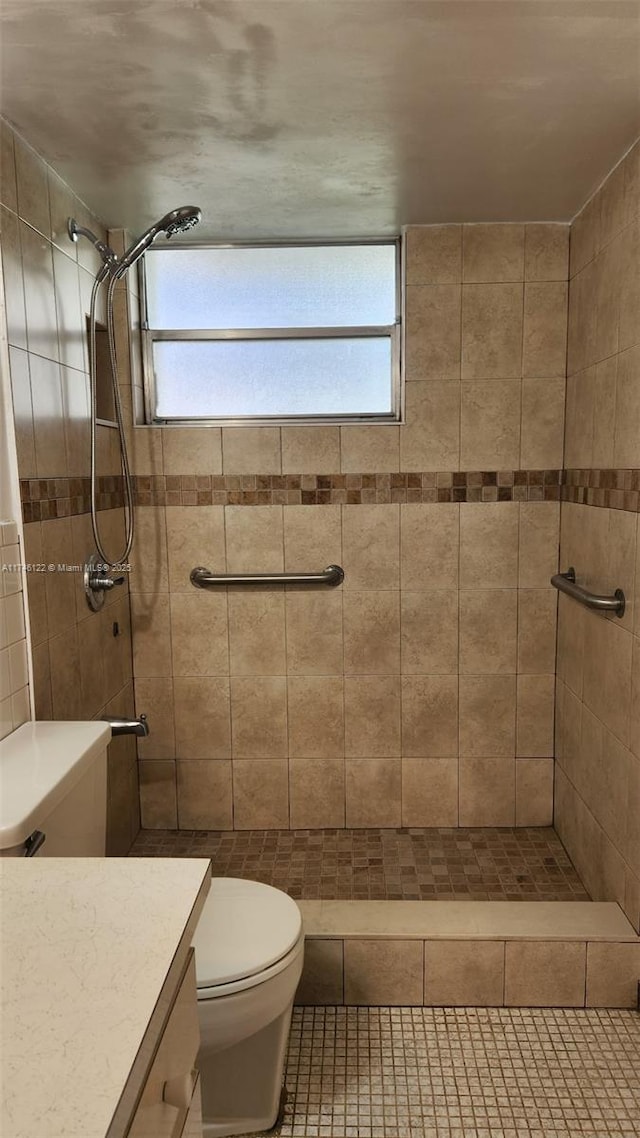 bathroom with tiled shower, vanity, toilet, and tile patterned floors