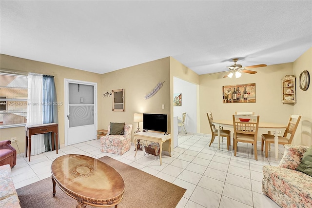 living area with a textured ceiling, ceiling fan, and light tile patterned flooring