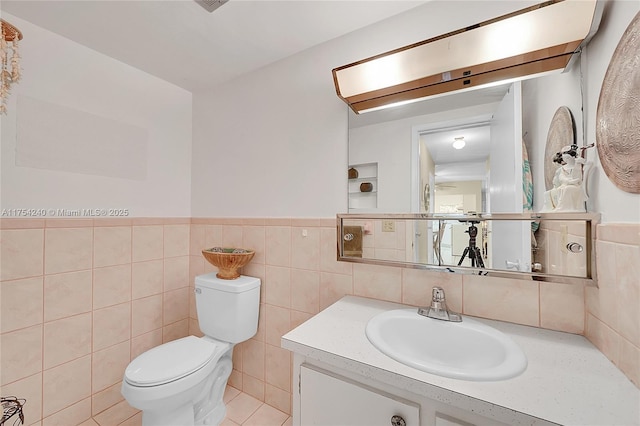 bathroom with wainscoting, vanity, toilet, and tile walls