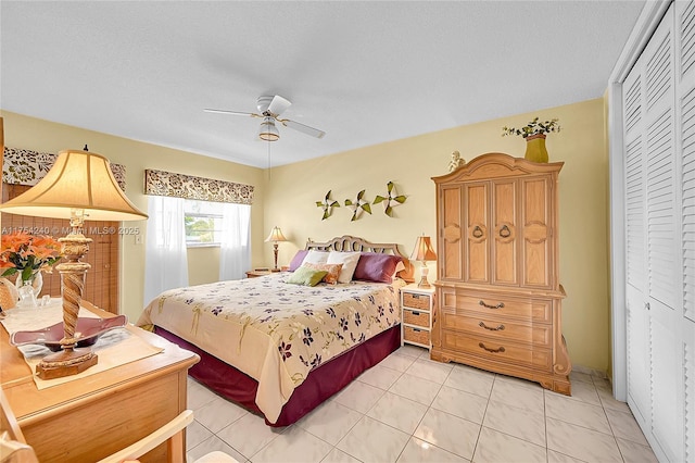 bedroom featuring a closet, light tile patterned flooring, ceiling fan, and a textured ceiling