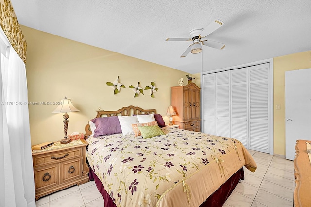 bedroom with a ceiling fan, a closet, light tile patterned flooring, and a textured ceiling