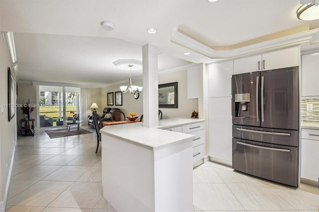 kitchen with crown molding, light countertops, white cabinetry, stainless steel fridge, and a peninsula