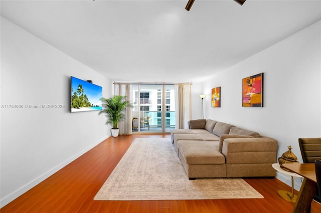 living area with expansive windows, wood finished floors, and baseboards