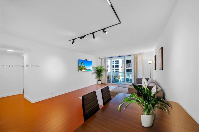 interior space featuring expansive windows, rail lighting, baseboards, and wood finished floors