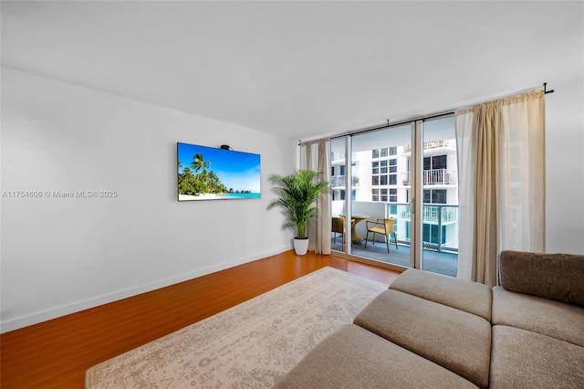 living area featuring expansive windows, baseboards, and wood finished floors