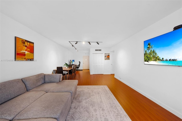 living room featuring rail lighting, visible vents, baseboards, and wood finished floors