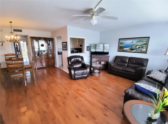 living area featuring a textured ceiling, visible vents, ceiling fan with notable chandelier, and light wood-style flooring