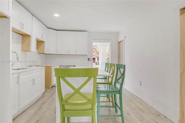 kitchen featuring white cabinetry, a sink, and light wood-style flooring