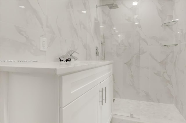 full bathroom with tile walls, vanity, and a marble finish shower