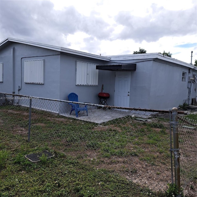 view of side of home with a patio, a yard, fence, and stucco siding