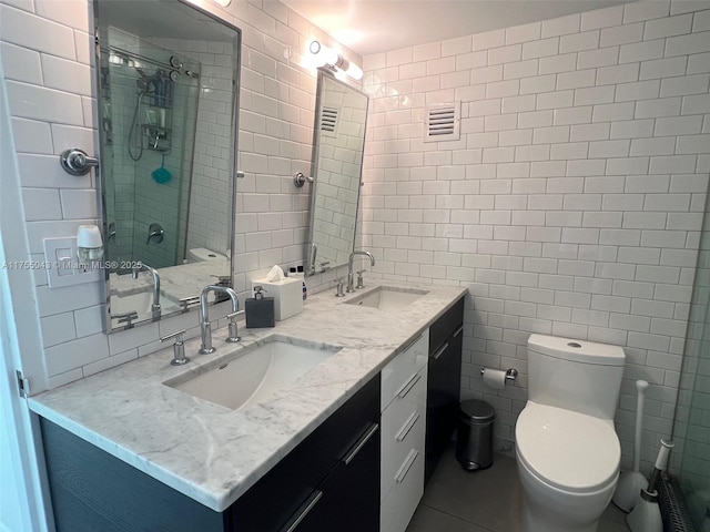 bathroom featuring a sink, tile walls, and toilet