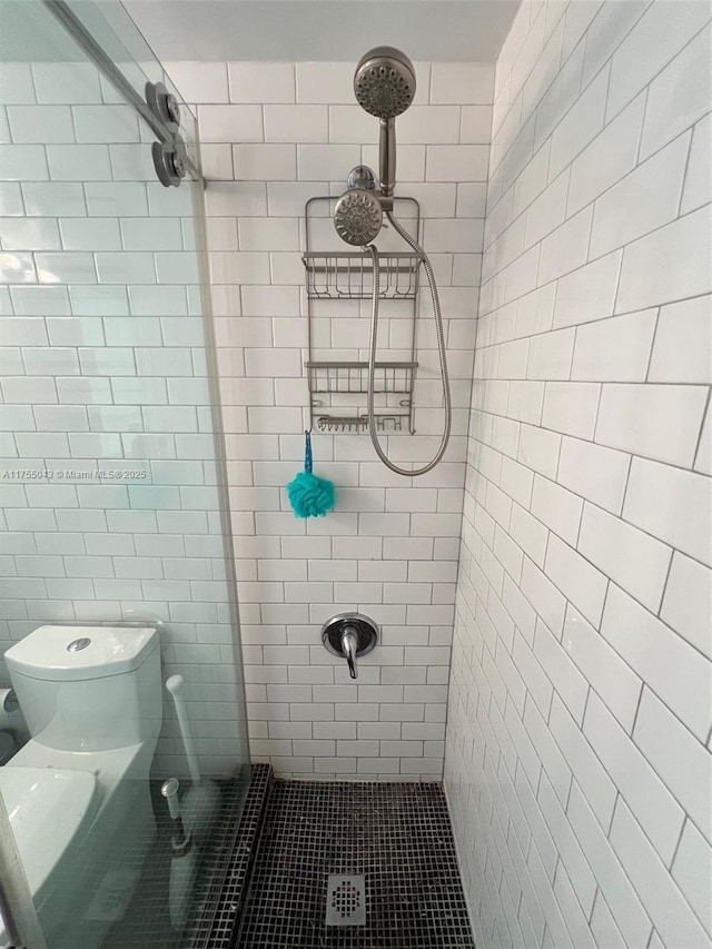 bathroom featuring tiled shower and toilet