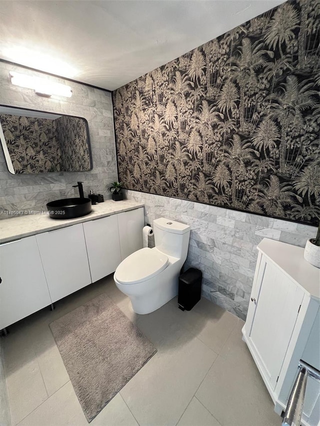 bathroom featuring a wainscoted wall, vanity, toilet, and wallpapered walls