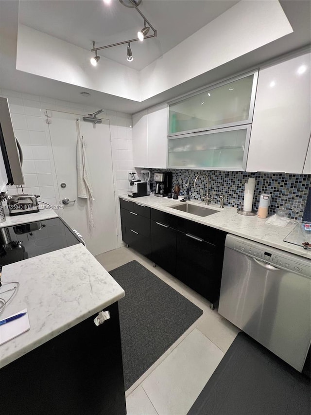 kitchen with a sink, white cabinets, stainless steel dishwasher, dark cabinetry, and backsplash