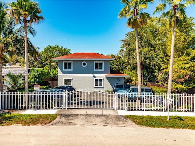 view of front facade featuring a fenced front yard, a gate, and stucco siding