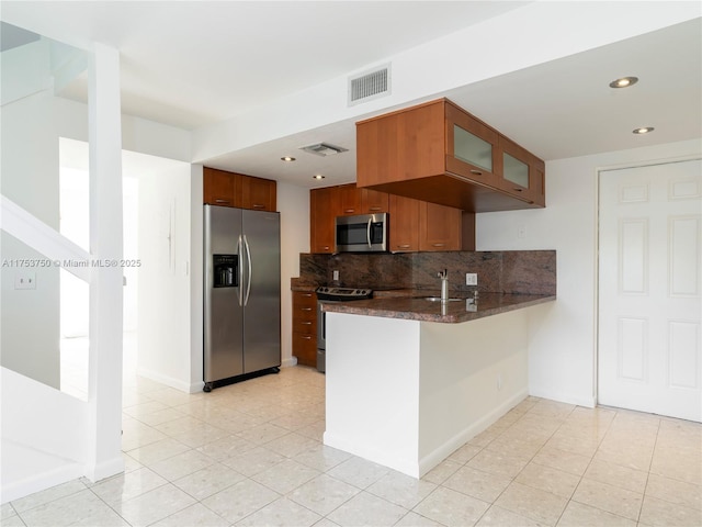 1323 NE 5th Ave, Fort Lauderdale, FL 33304 - kitchen featuring stainless steel appliances, a peninsula, glass insert cabinets, a sink, and decorative backsplash