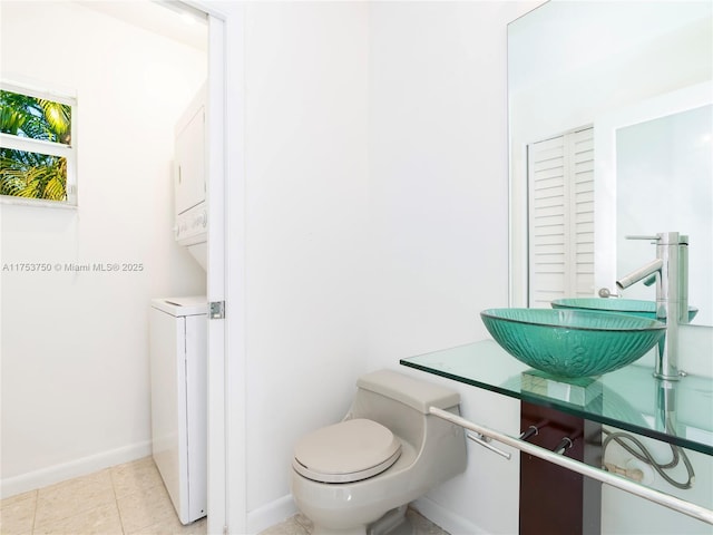 1323 NE 5th Ave, Fort Lauderdale, FL 33304 - bathroom featuring stacked washer / dryer, toilet, baseboards, and a sink