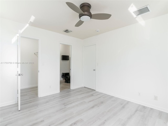 1323 NE 5th Ave, Fort Lauderdale, FL 33304 - unfurnished bedroom featuring wood finished floors, a spacious closet, a closet, ensuite bath, and baseboards