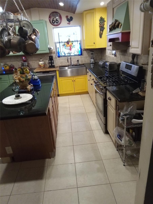 kitchen featuring light tile patterned floors, premium range hood, a sink, decorative backsplash, and gas range