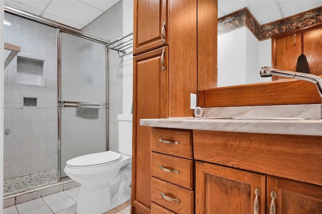 full bathroom featuring a paneled ceiling, toilet, vanity, a shower stall, and tile patterned floors