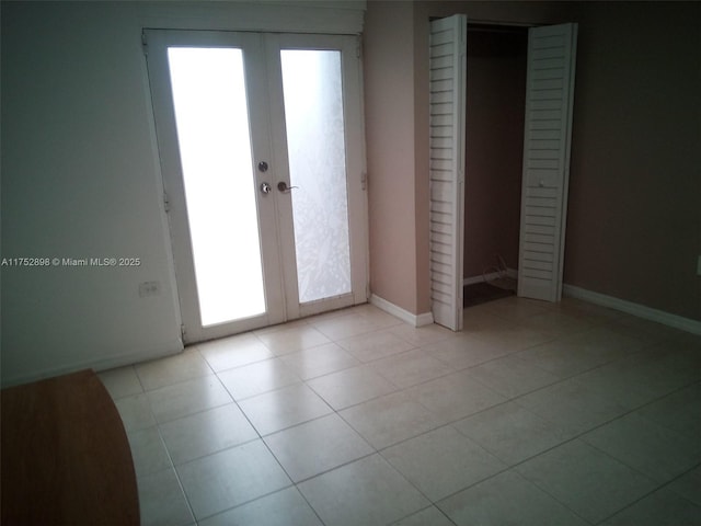 unfurnished bedroom with light tile patterned flooring, baseboards, and french doors