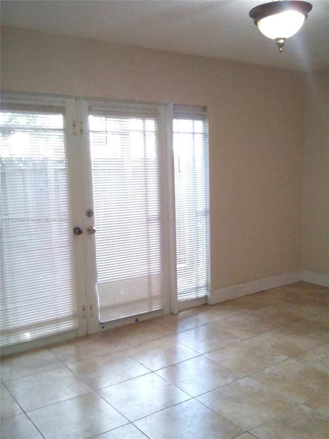 spare room with french doors, baseboards, and light tile patterned floors