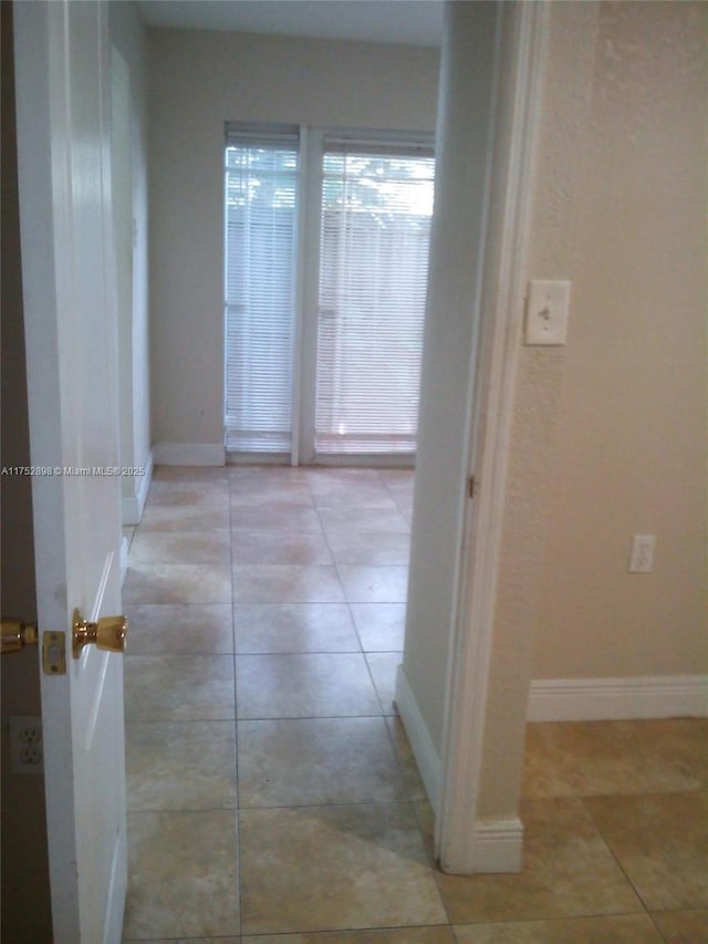 hall with light tile patterned flooring and baseboards