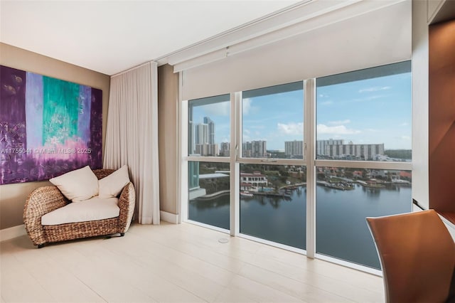 sitting room with a city view, a water view, and baseboards