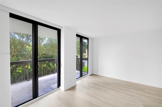 empty room with floor to ceiling windows and wood finished floors