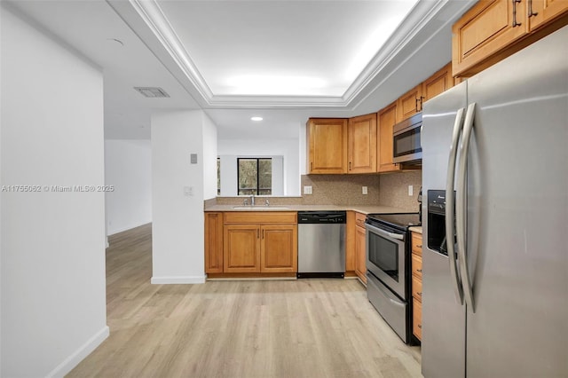 kitchen with a raised ceiling, visible vents, appliances with stainless steel finishes, a sink, and light wood-type flooring