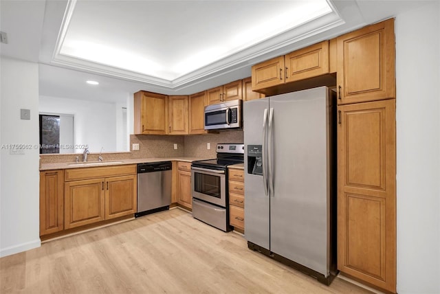 kitchen with decorative backsplash, stainless steel appliances, light countertops, light wood-style floors, and a sink