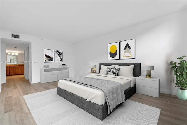 bedroom featuring baseboards, visible vents, and light wood finished floors