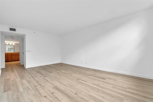 unfurnished room with visible vents, light wood-style flooring, and baseboards