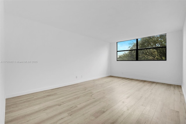 unfurnished room with baseboards and wood finished floors