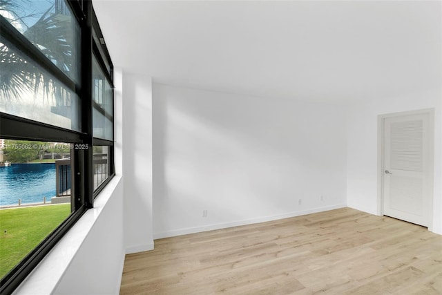 unfurnished room with a water view, baseboards, and wood finished floors