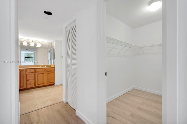 walk in closet with a sink and light wood-style floors