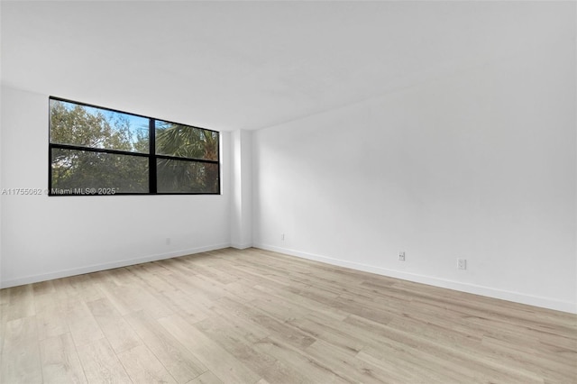 unfurnished room with light wood-style flooring and baseboards